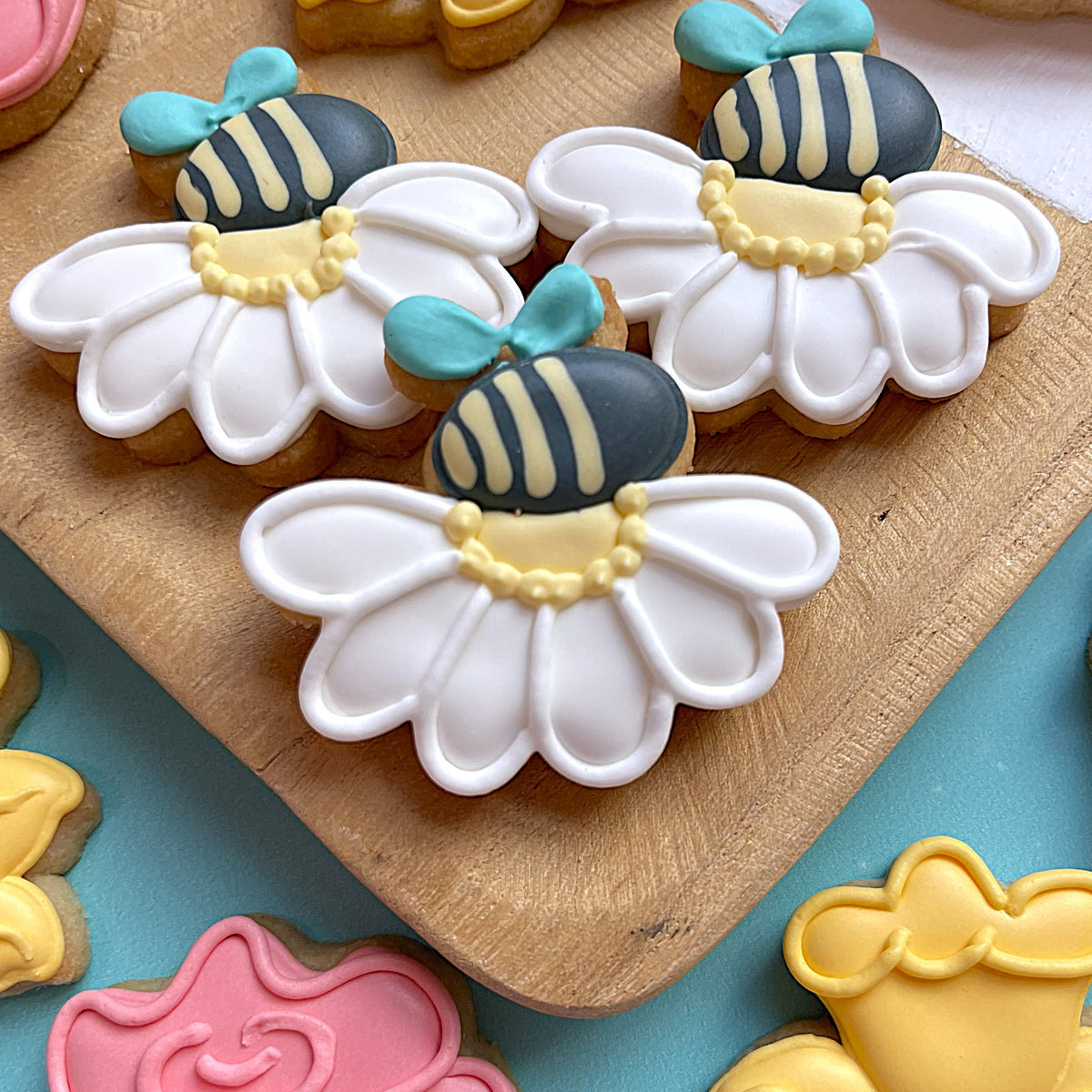 Mini flower cookie cutter bundle with delicate white daisy sugar cookies yellow center dark blue bees and turquoise bows