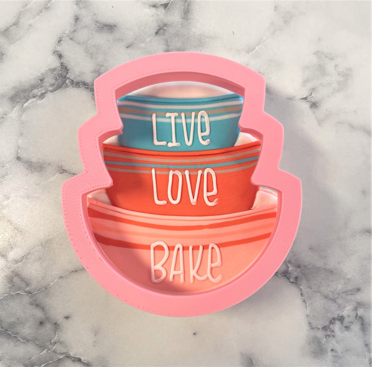 Pink silicone stacked bowls cookie cutter with live love bake text in white for baking and decorating cookies