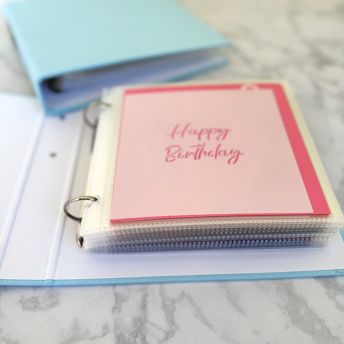 A clear plastic page protector holding a pink happy birthday card with red trim from stencil color backers 50 color square inserts