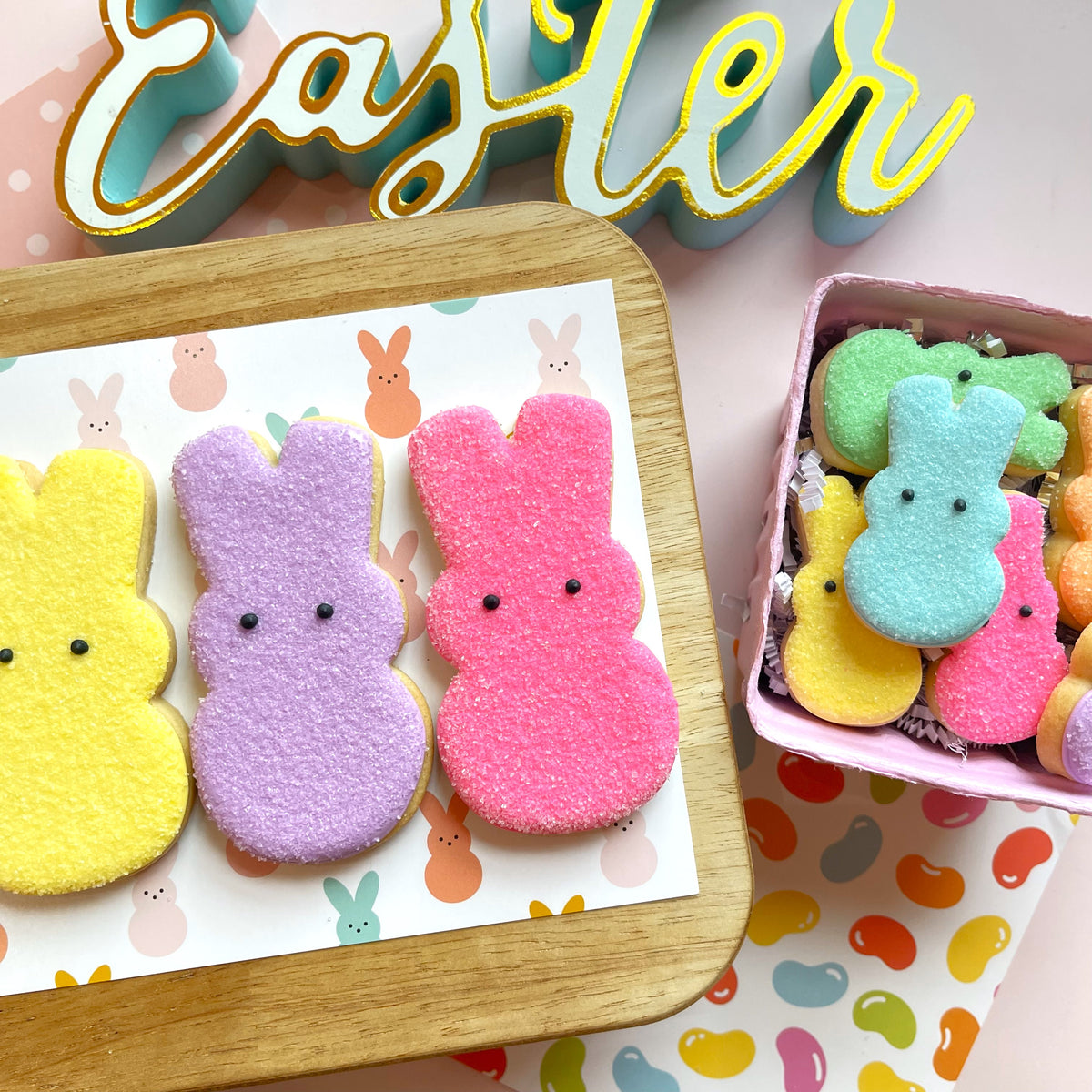 Pastel-colored sugar-coated bunny peep cookies arranged on a wooden tray made with bunny peep flour box cookie cutter