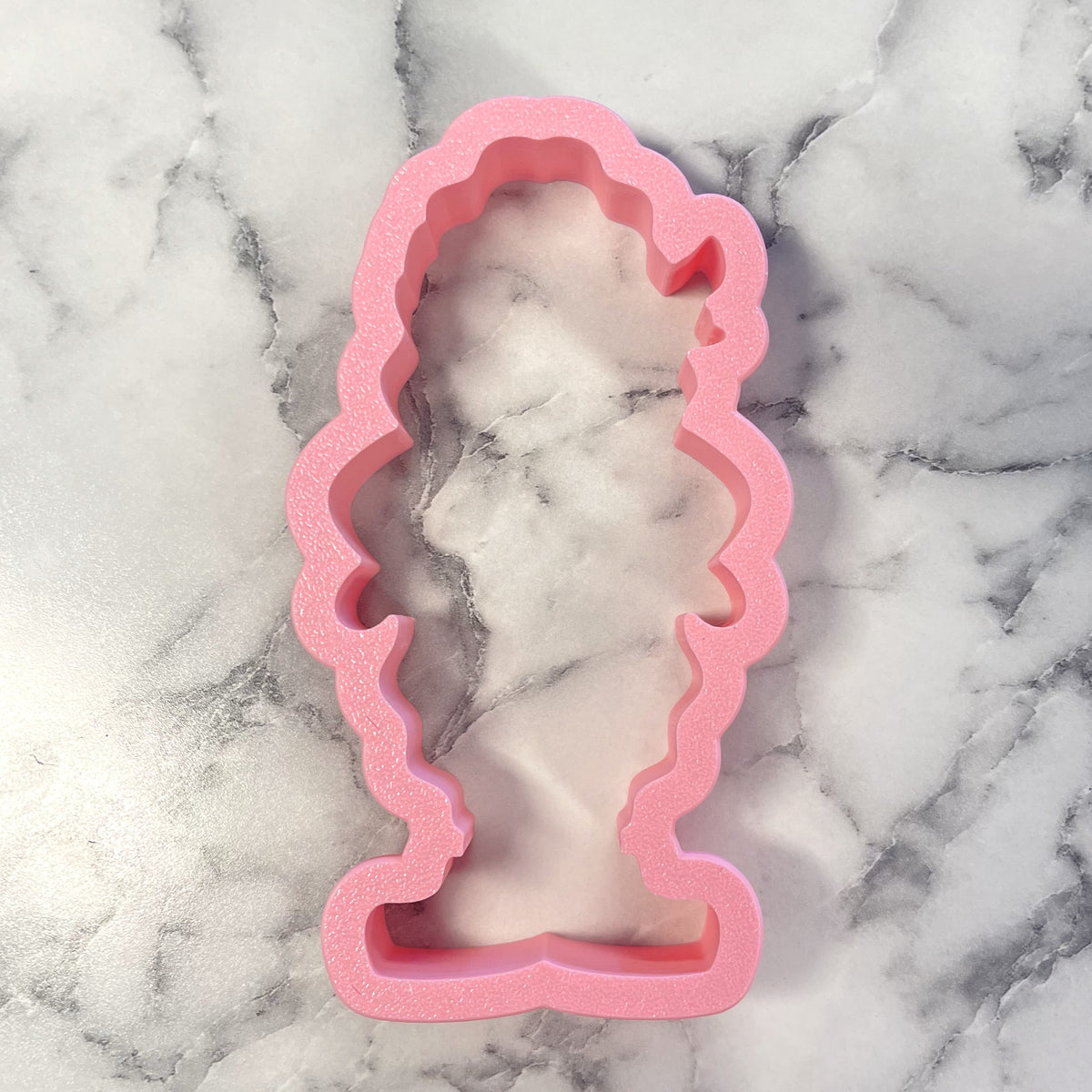 Pink foam pickle baller cookie cutter shaped like a stylized figure with curly hair for fun baking designs