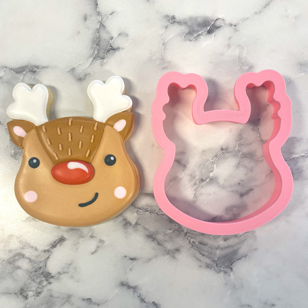 Pink plastic cute reindeer face cookie cutter with heart shaped antlers for festive baking and decorating
