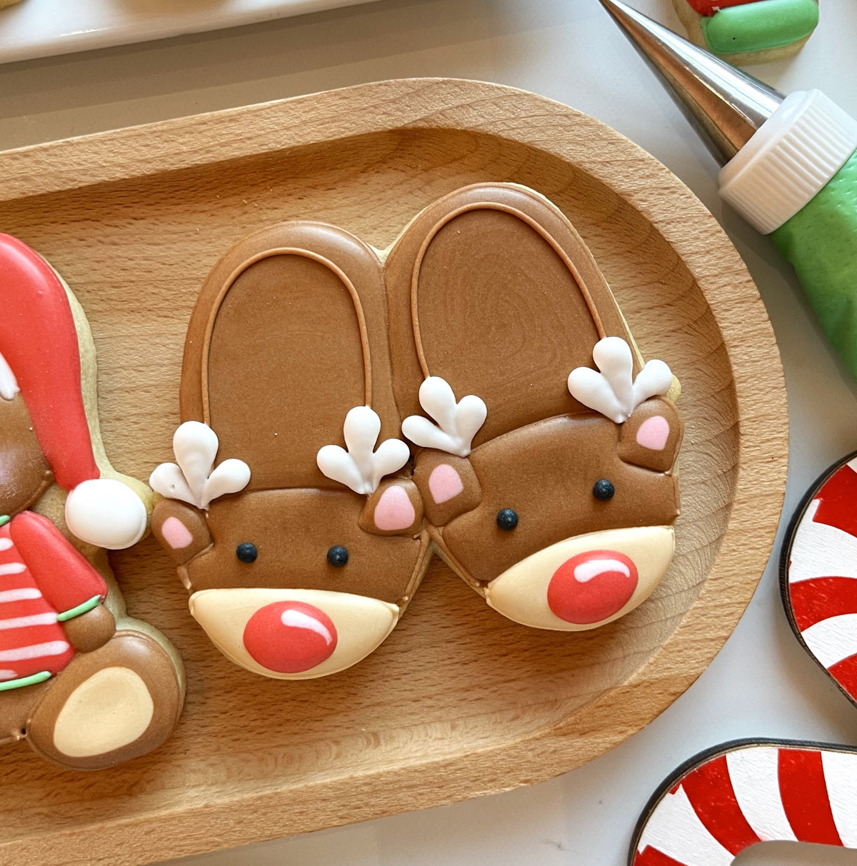 Two chocolate-brown reindeer sugar cookies with white antlers pink cheeks black eyes and red noses from christmas pajamas cookie cutter bundle