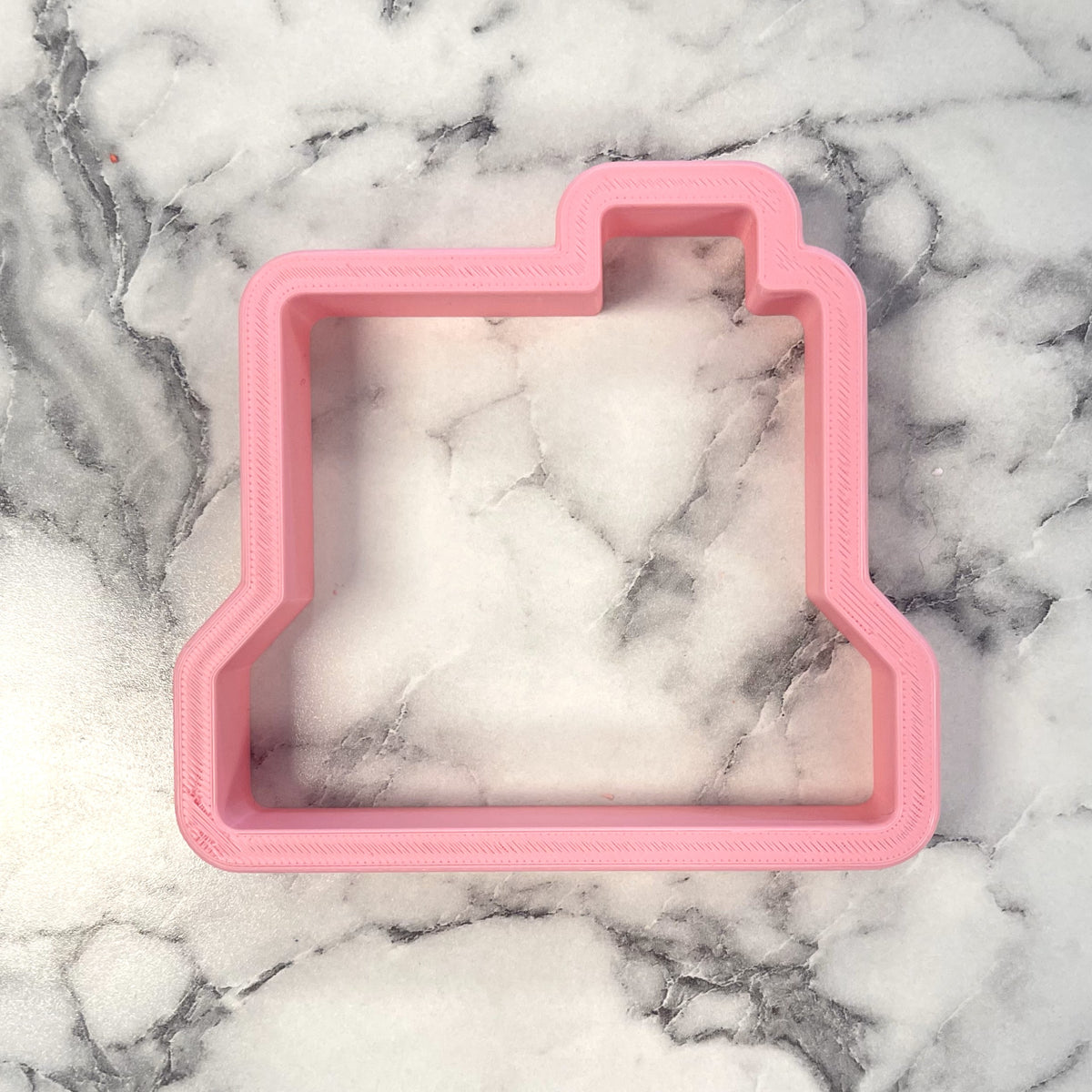 Pink plastic retro camera cookie cutter for baking shaped like a vintage camera design