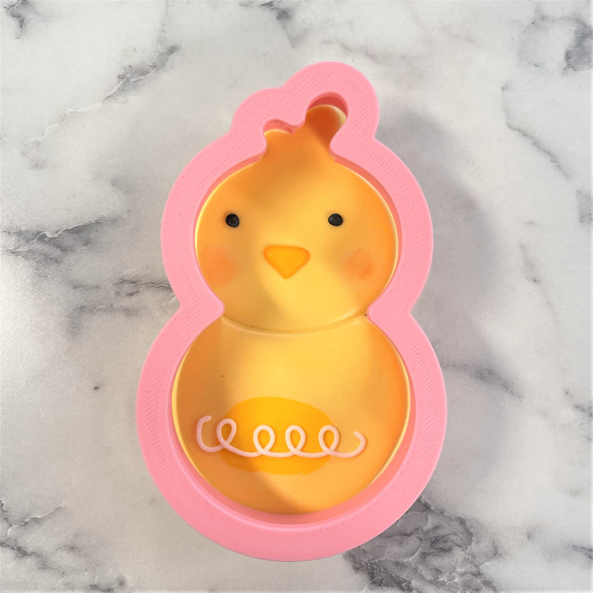 Pink silicone chicken-shaped cookie cutter with yellow interior black eyes orange beak for chick roly poly flour box club