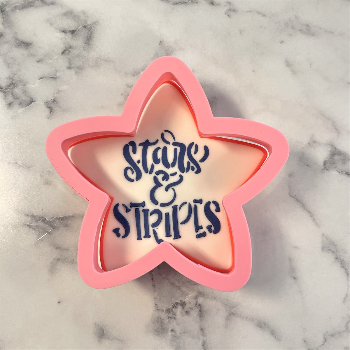 Pink star-shaped rounded star flour box club cookie cutter with navy blue stars and stripes script design