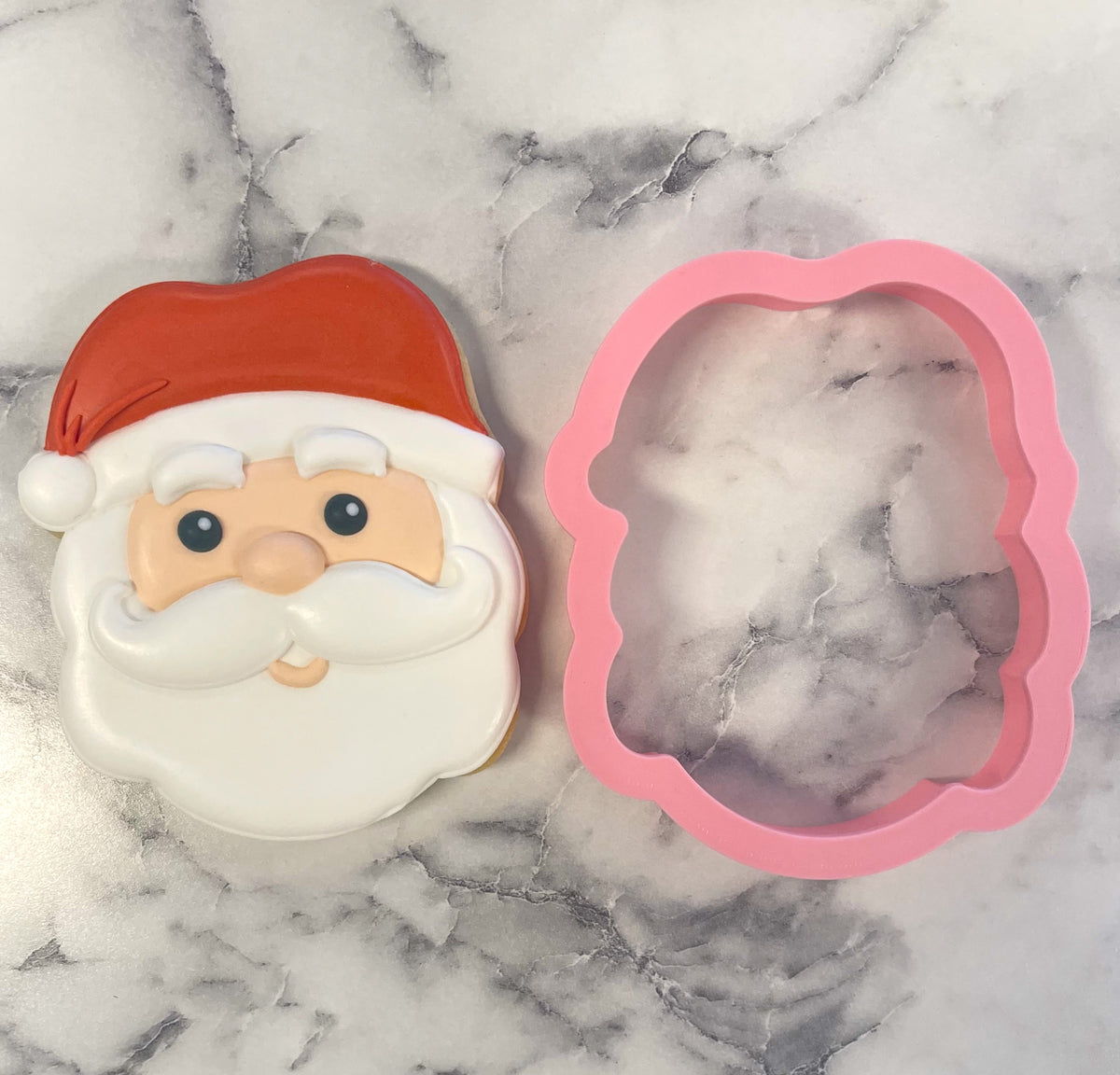 Cute santa face cookie cutter made of pink silicone featuring a red hat and white beard design for holiday baking