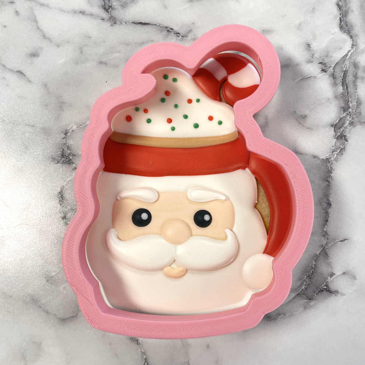 Pink plastic santa mug cookie cutter with red hat and white beard details for festive baking use