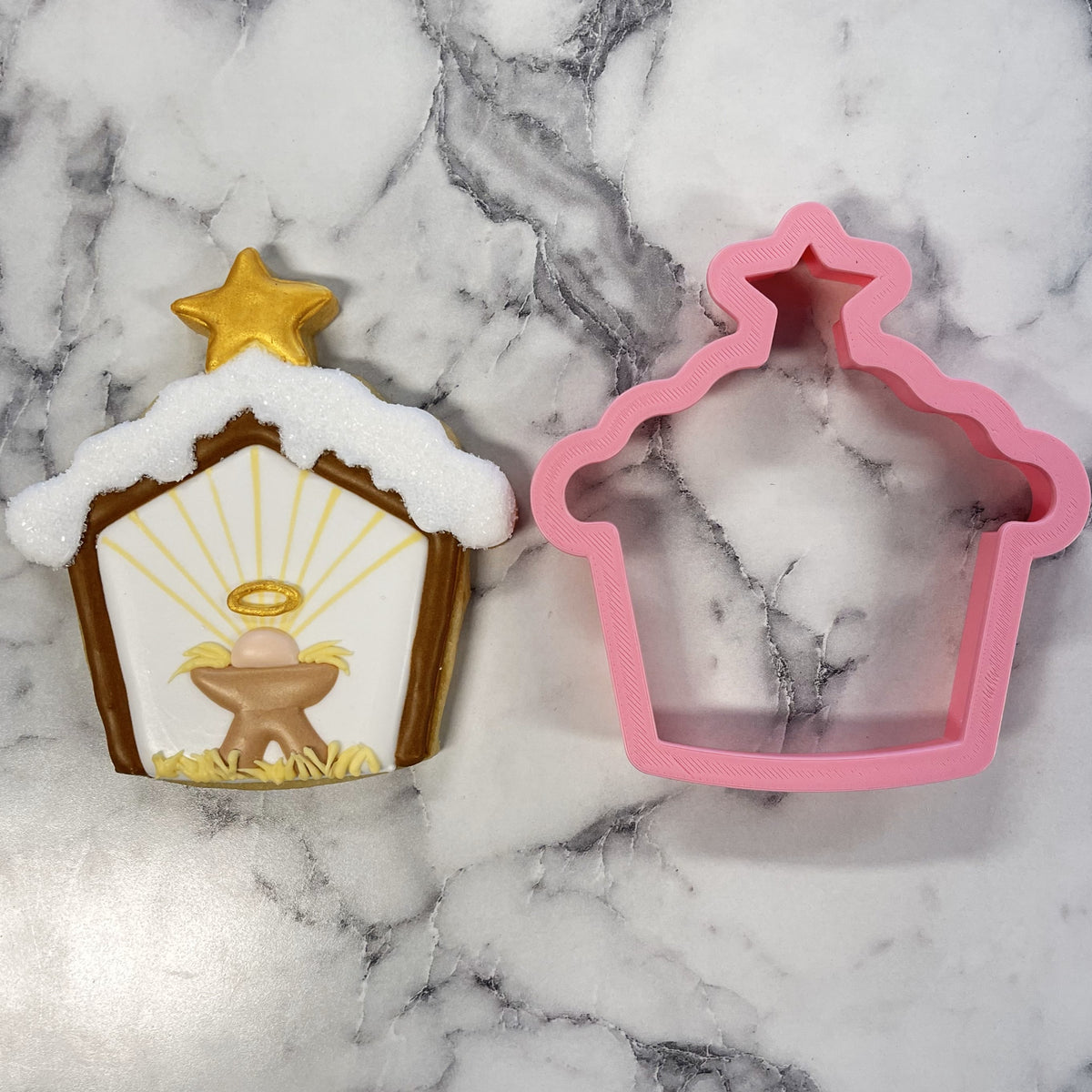 Pink plastic Christmas nativity stable cookie cutter with star-shaped top for snowy stable holiday baking