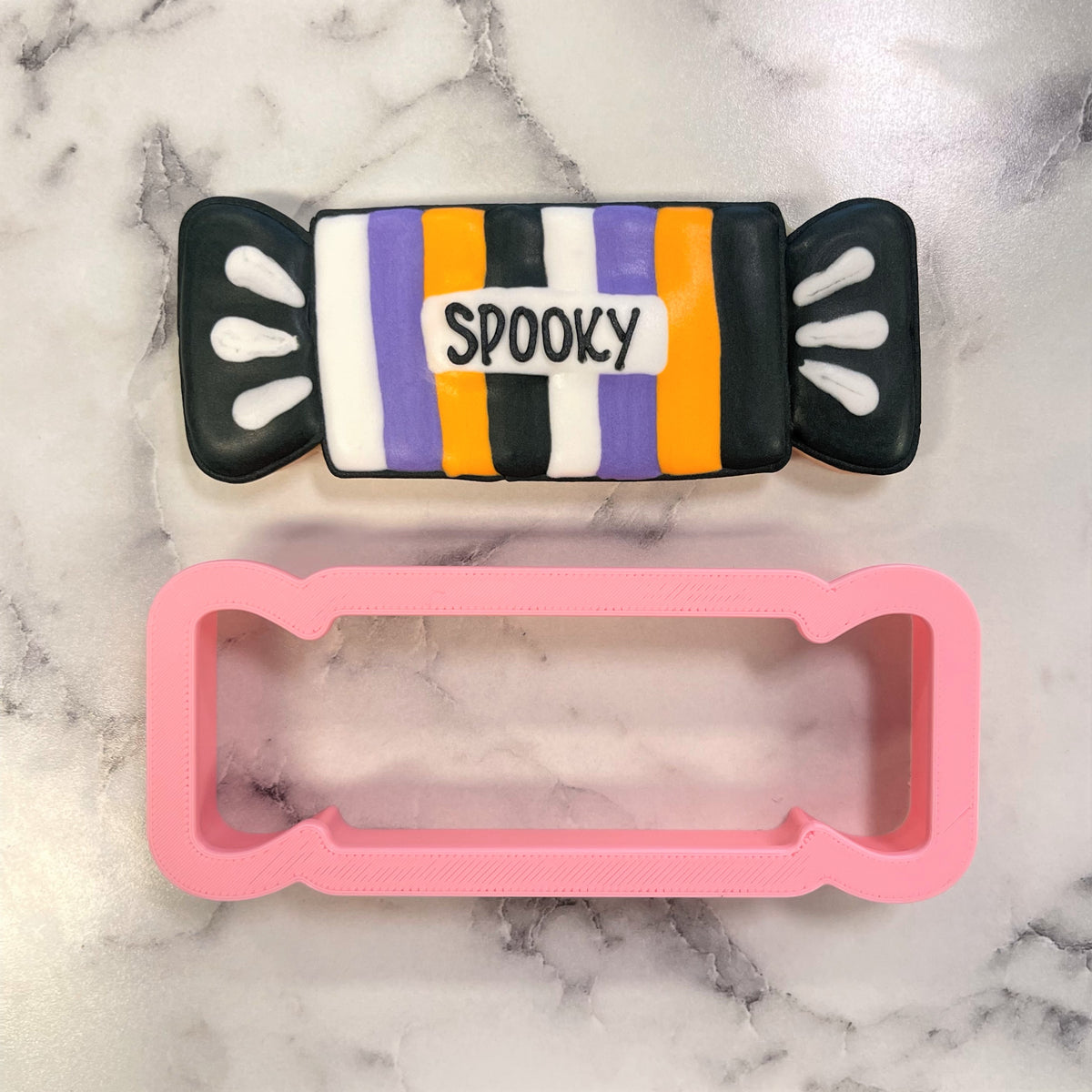 Wrapped long candy cookie cutter in pink plastic with halloween striped pattern for festive cookie decorating