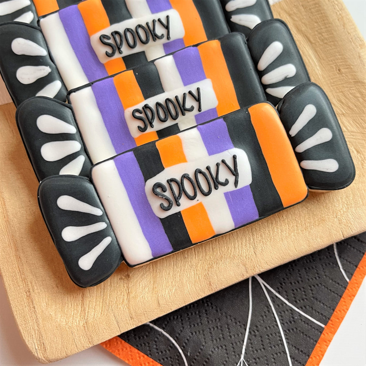 Wrapped long candy cookie cutter used to make Halloween candy bar cookies with black orange purple stripes and spooky icing