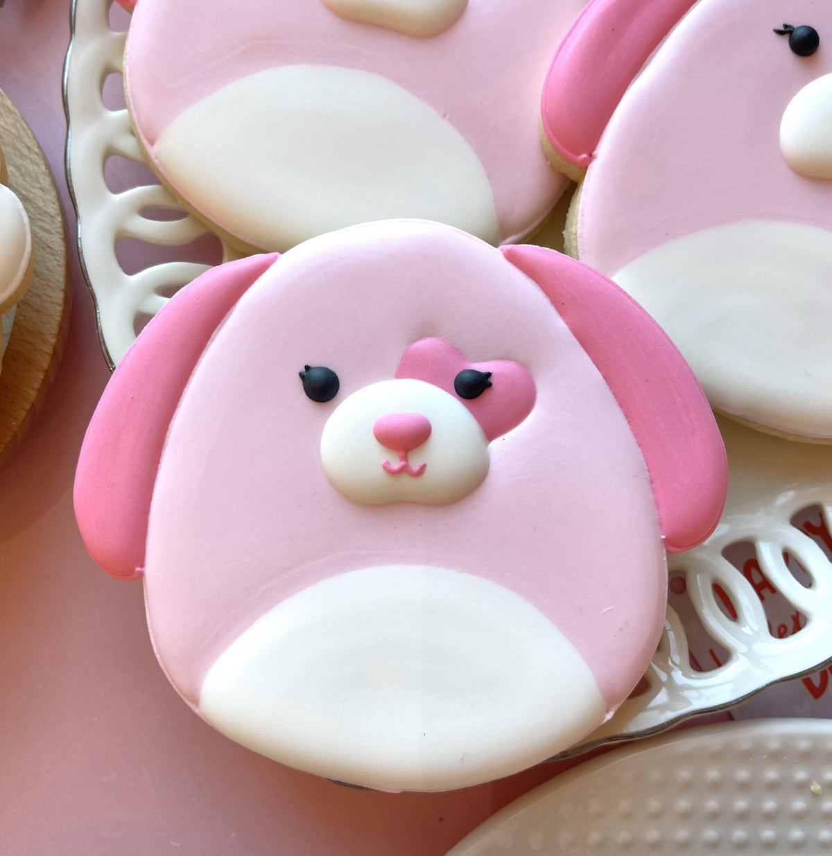Pink and white frosted squishie valentine bunny cookie with black button eyes and floppy ears from decorating kit