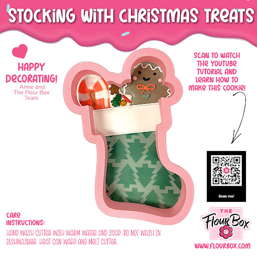 A pink-handled stocking shaped cookie cutter with green patterned fabric and white trim for Christmas treats