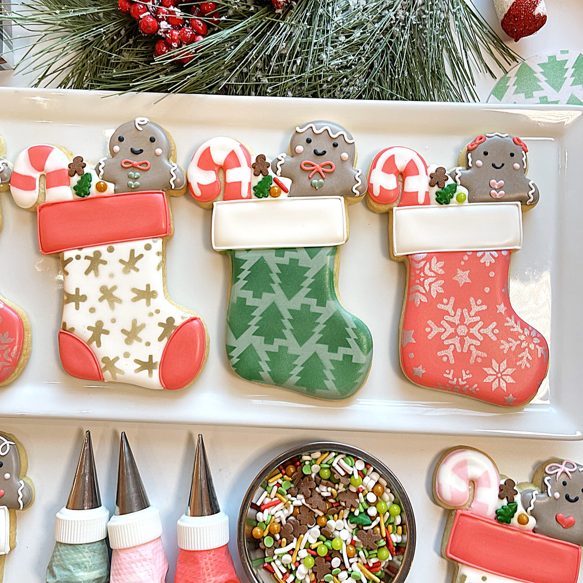 Three intricately decorated christmas stocking cookies with festive patterns and gingerbread man toppers cut with a cookie cutter