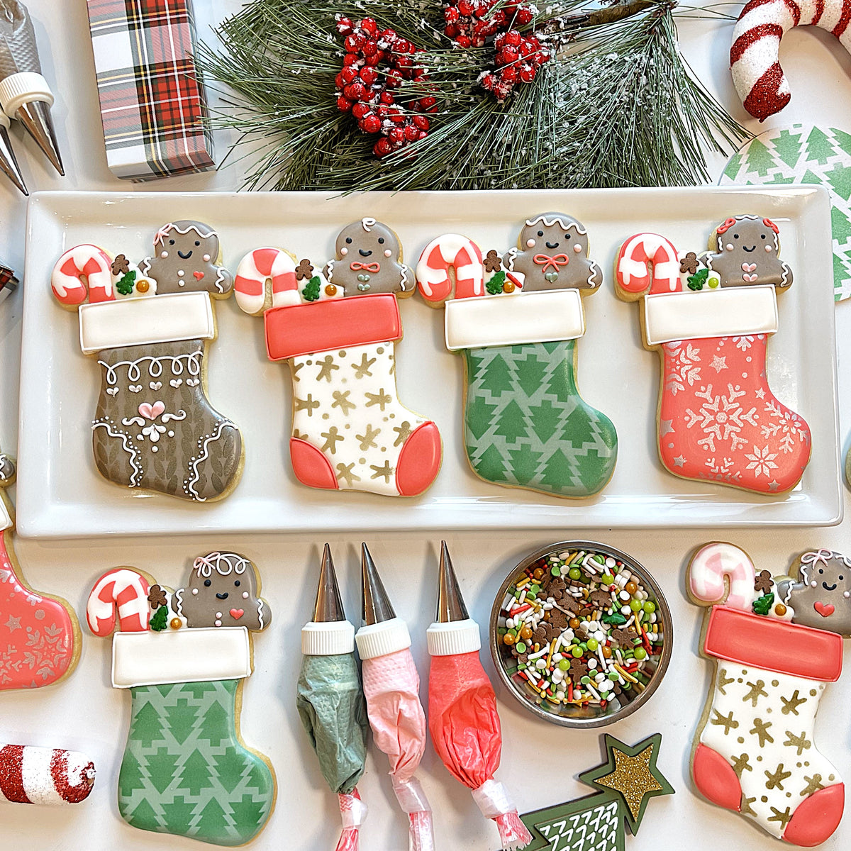 Four gingerbread cookie stockings with smiling gingerbread men and intricate red green gold icing for christmas treats