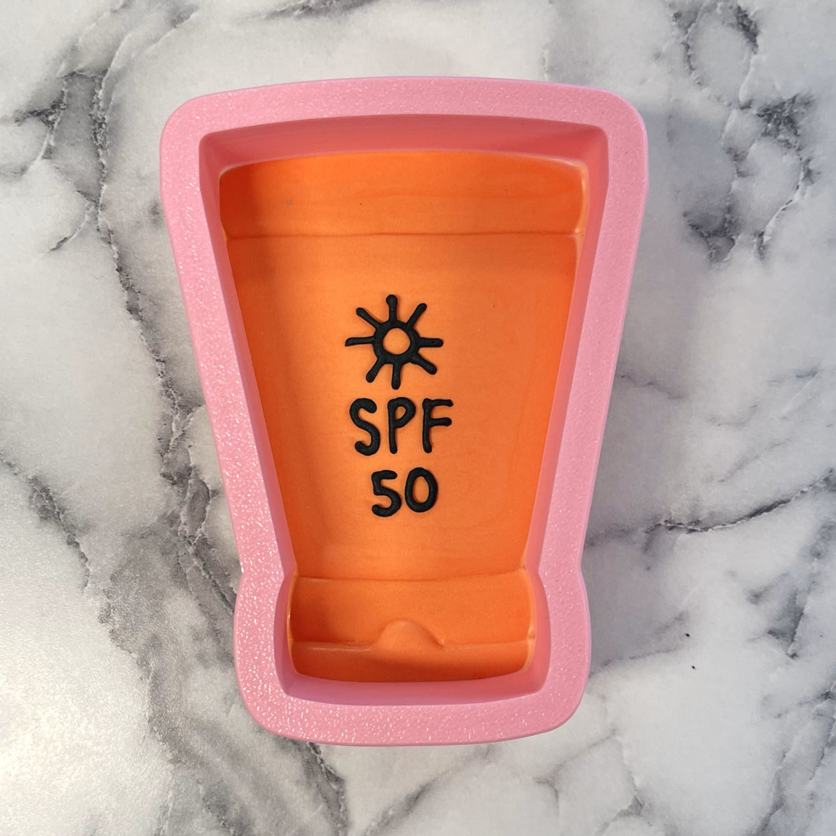 Pink silicone sunscreen cookie cutter shaped like an orange spf 50 bottle for baking and crafting use