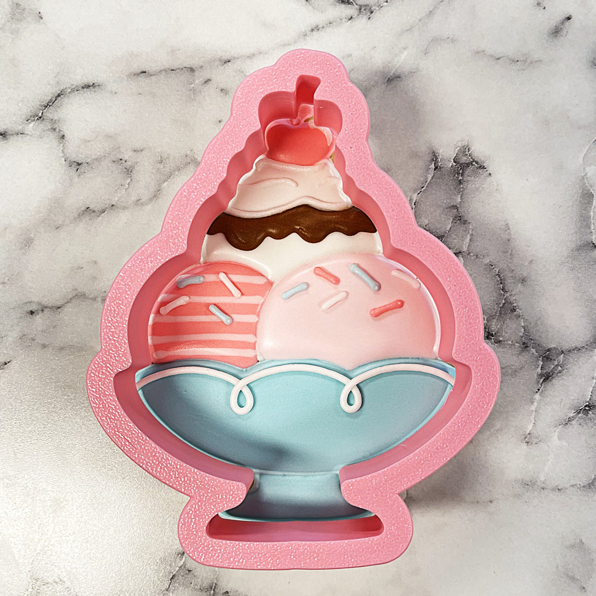 Pink glittery silicone sundae with heart cherry cookie cutter featuring a light blue bowl and striped pink and white scoop