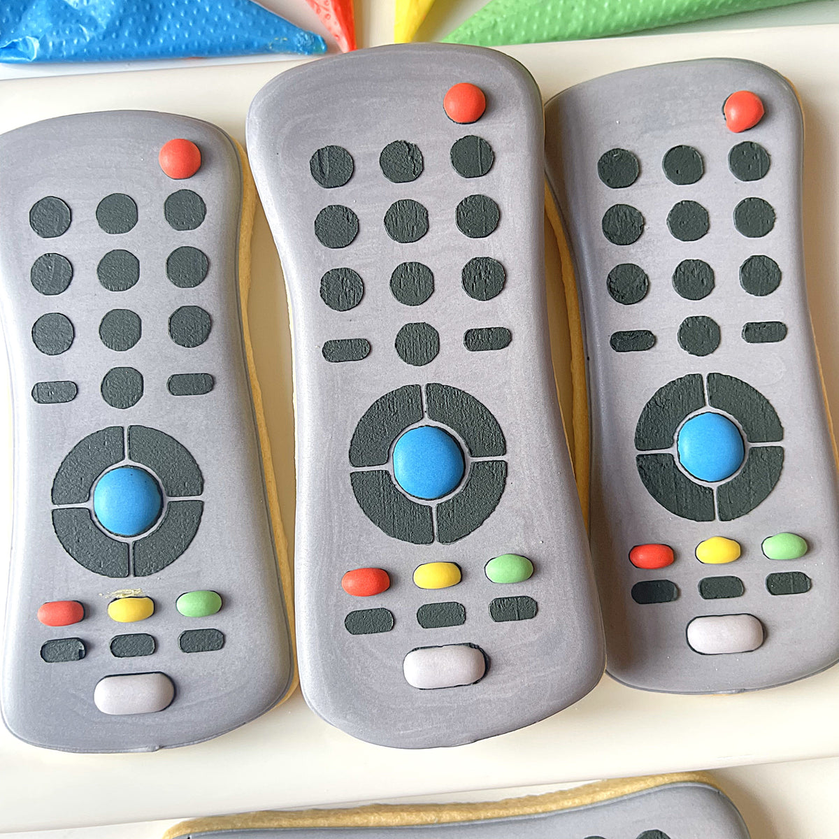 Gray sugar cookies shaped like remote controls with colorful candy buttons and blue dial from father’s day 2025 cutter set