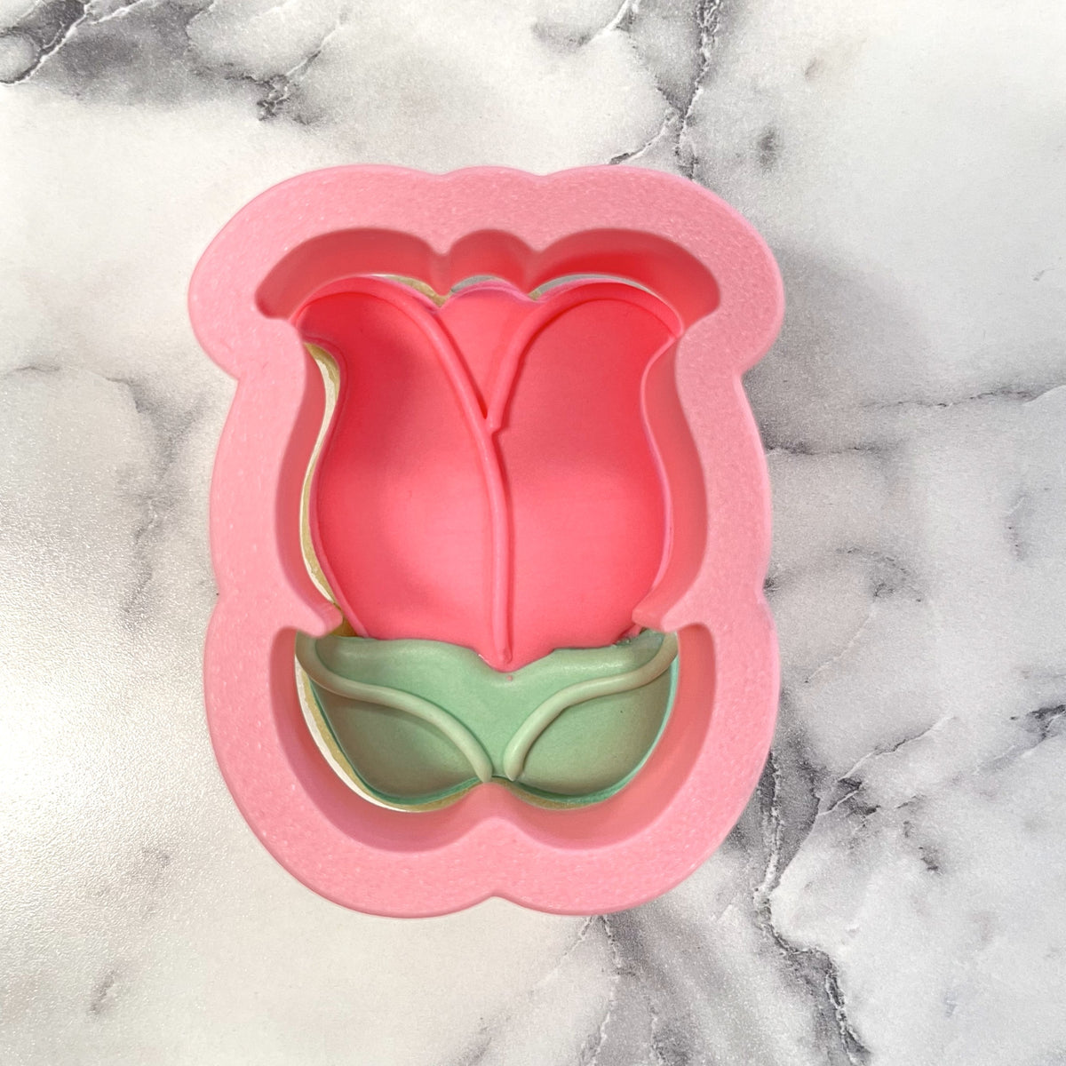 Mini tulip with leaves cookie cutter in pink silicone with a green base for shaping tulip-shaped cookies