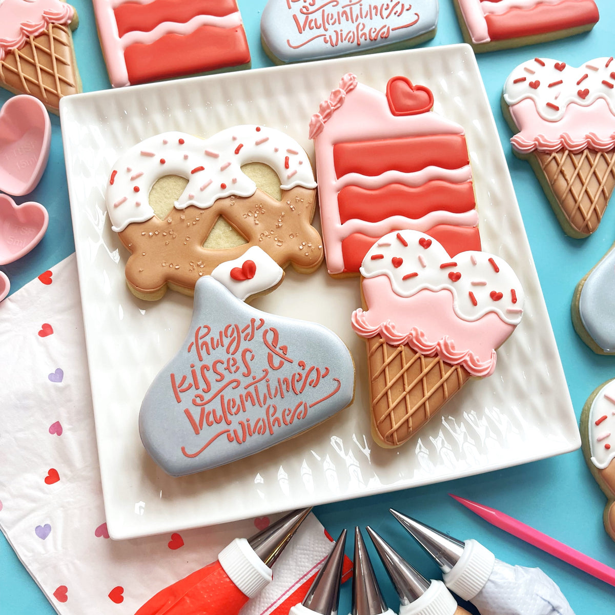 A light blue glossy valentine treats cookie shaped like a hershey’s kiss with pink hugs and kisses valentines wishes text