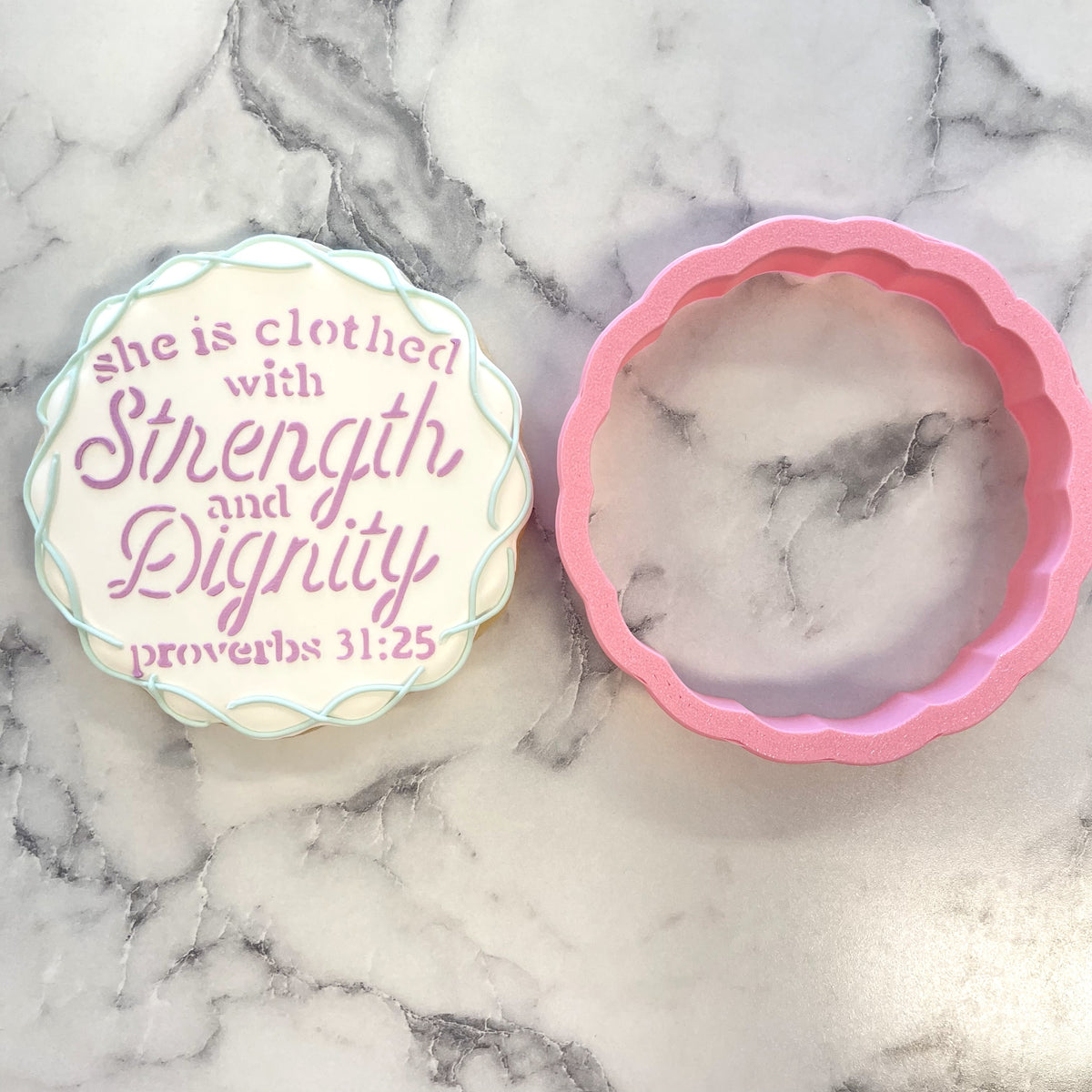 A round scalloped-edged decorative cookie with cream base and purple cursive text from proverbs 31 25 cutter and stencil bundle