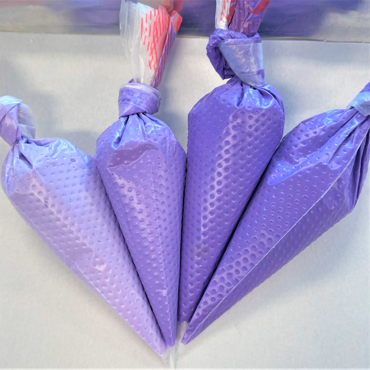 Purple silicone pastry bags with textured dotted surface and tied tops for violet the sugar art gel color use
