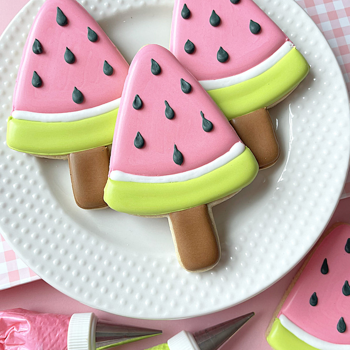 Pink and lime green watermelon popsicle shaped cookies with black seed details made using watermelon pop cookie cutter