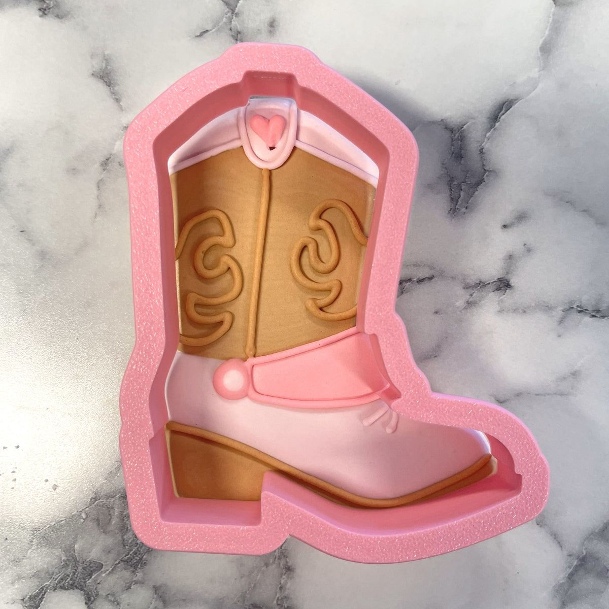 Pink glittery silicone western boot cookie cutter with tan and pink details and heart-shaped buckle design