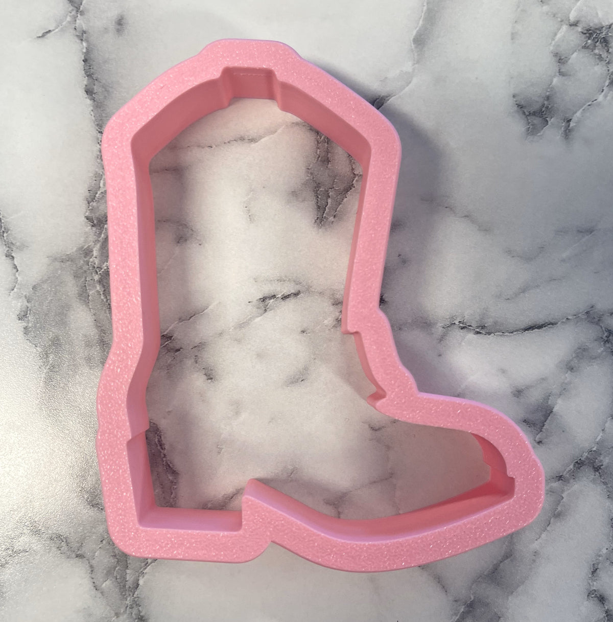 Pink glittery plastic western boot cookie cutter for baking shaped like a cowboy boot