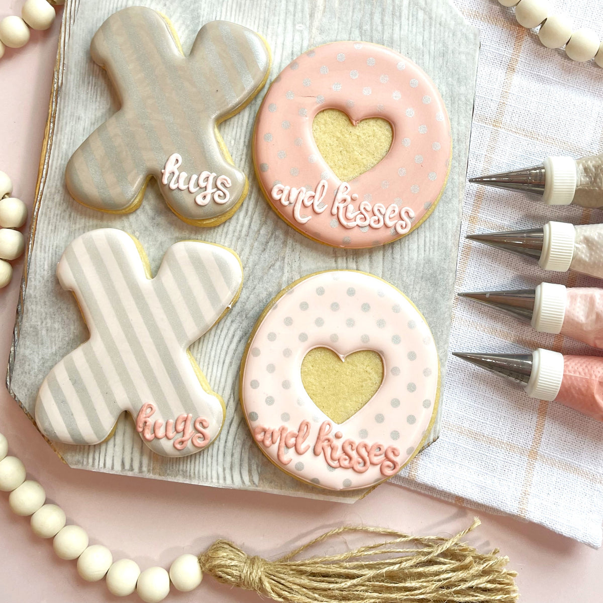 Delicate pink and white polka-dotted heart-shaped cookies with hugs and kisses icing made with xo cookie cutter bundle
