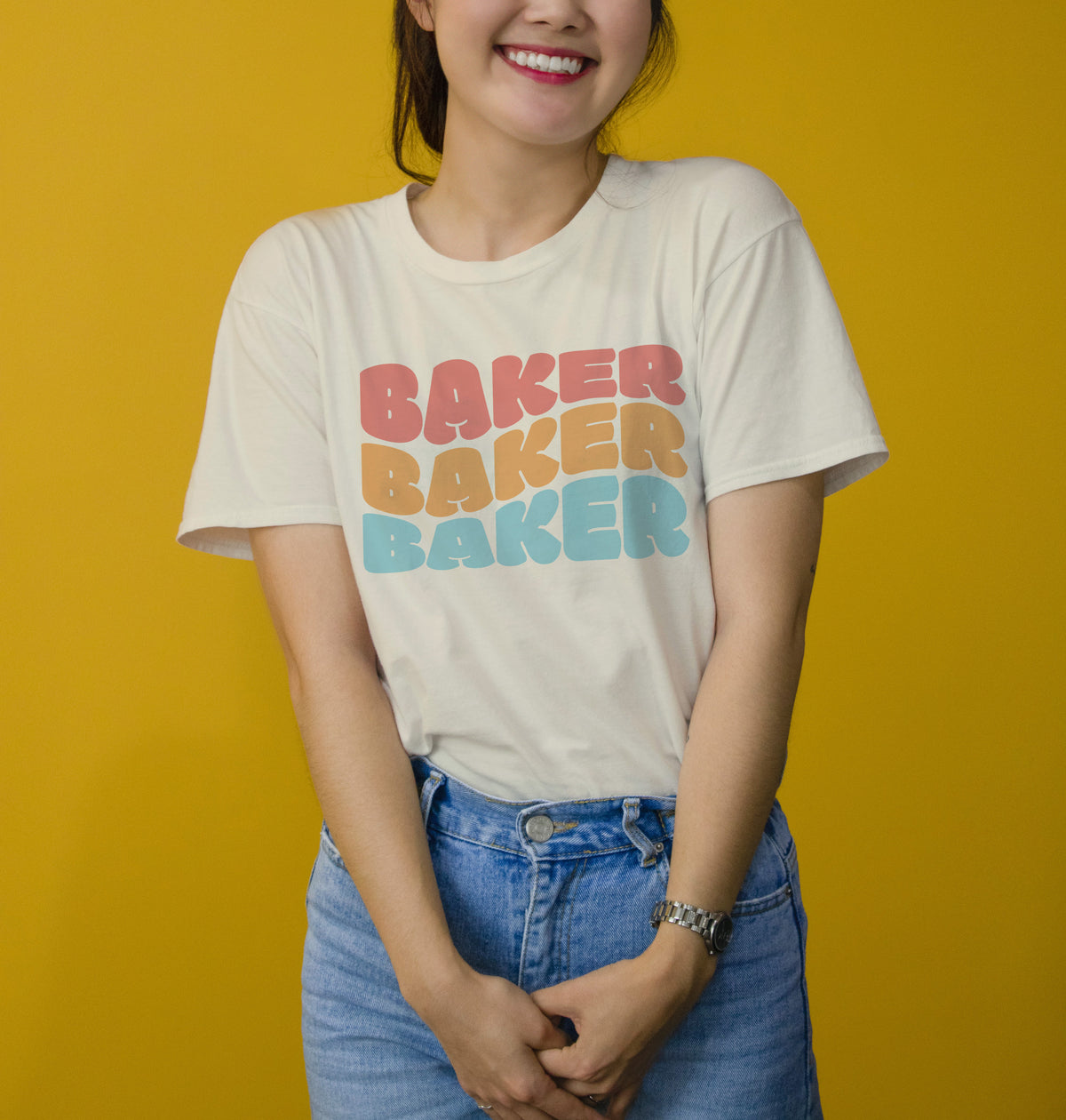 Cream-colored cotton t-shirt with bold stacked baker baker baker graphic in gradient pink orange and teal lettering
