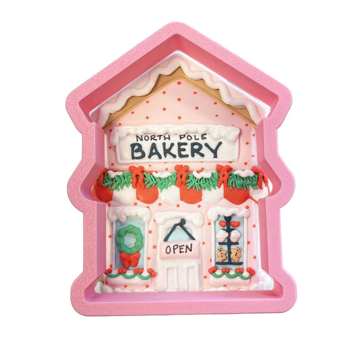 Pink glittery silicone bakery cookie cutter shaped like a miniature north pole bakery with white icing details