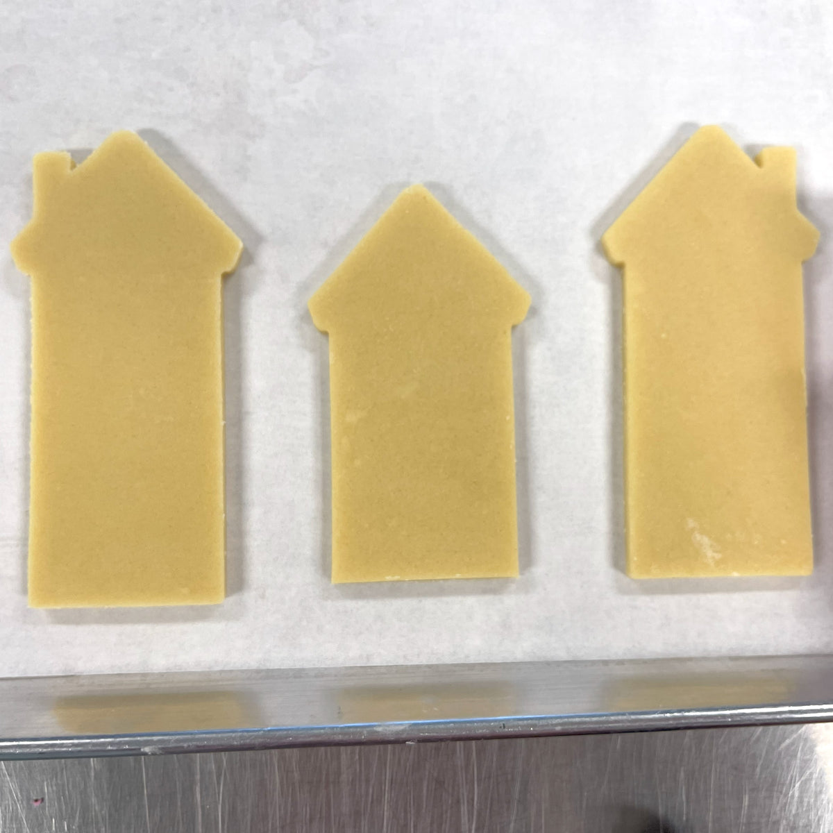 Three pale yellow house-shaped chocolates made with tall building flour box club cookie cutter for baking