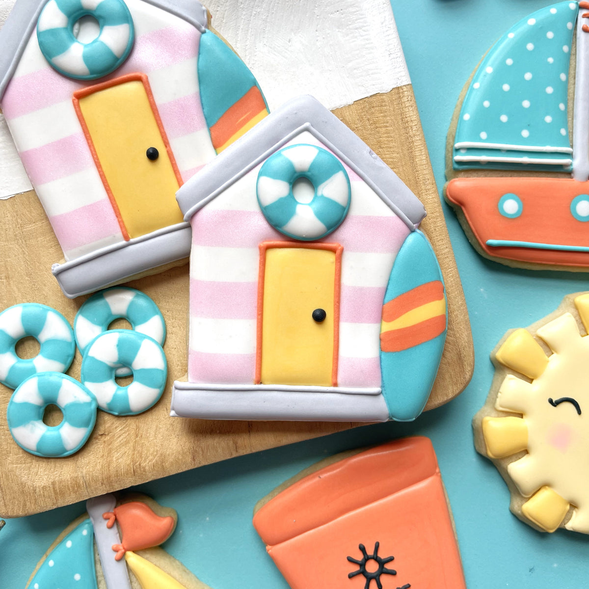 Pastel pink and white striped beach hut cookie with yellow door turquoise life preserver and surfboard accents