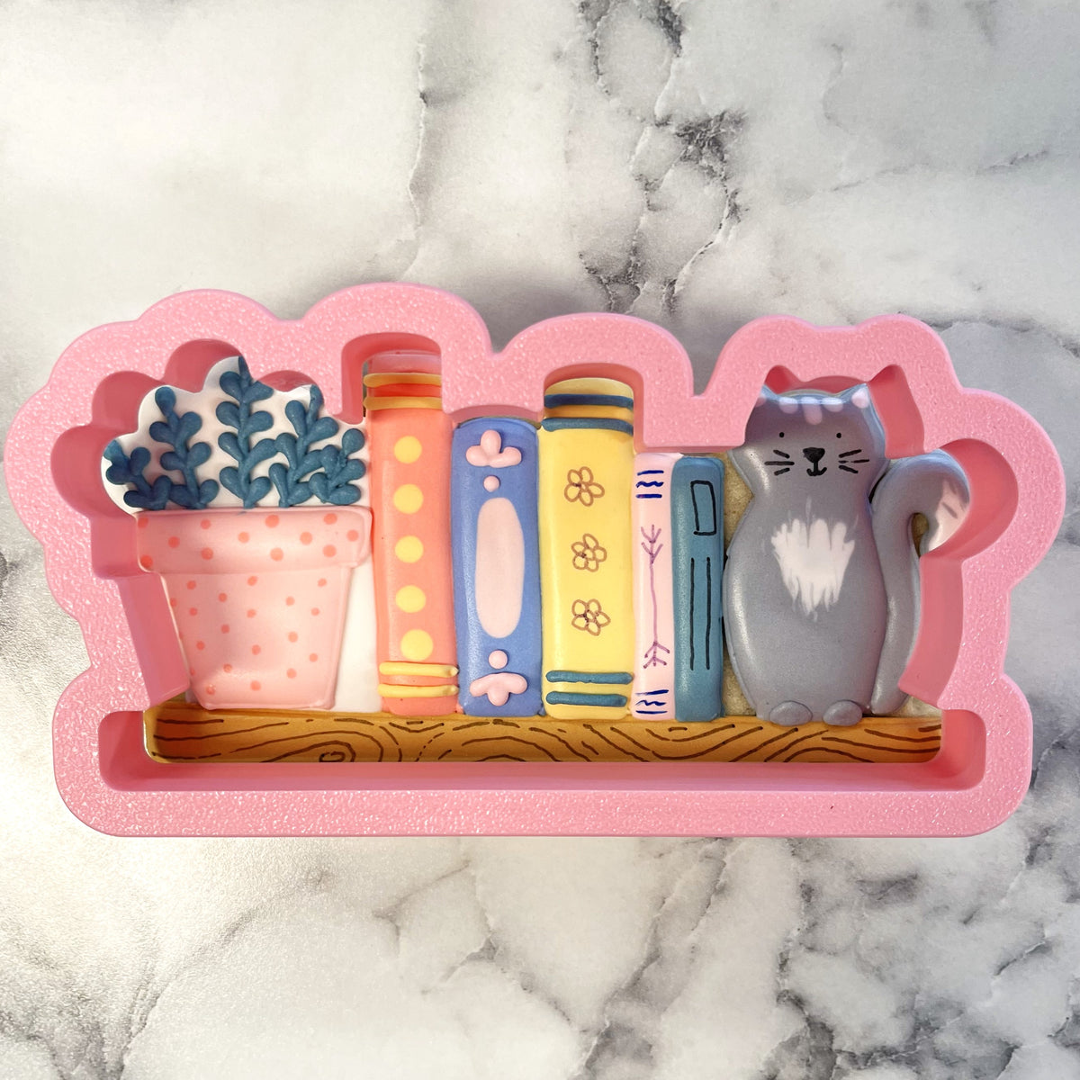 Pink silicone bookshelf mold with colorful books potted plant with blue leaves and gray cat figurine for cookies