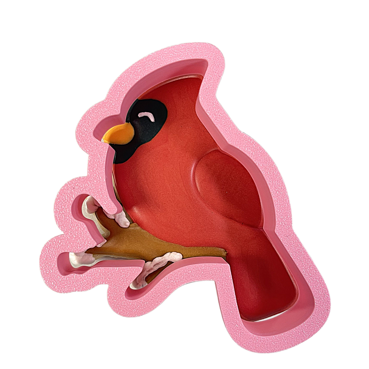 Pink foam cardinal on branch cookie cutter with black face yellow beak and white feet perched on brown branch