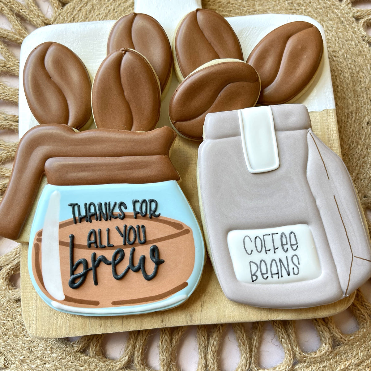 Chocolate-frosted coffee-themed sugar cookies shaped like a pour-over brewer and bean bag with decorative icing text from coffee brew cookie cutter bundle