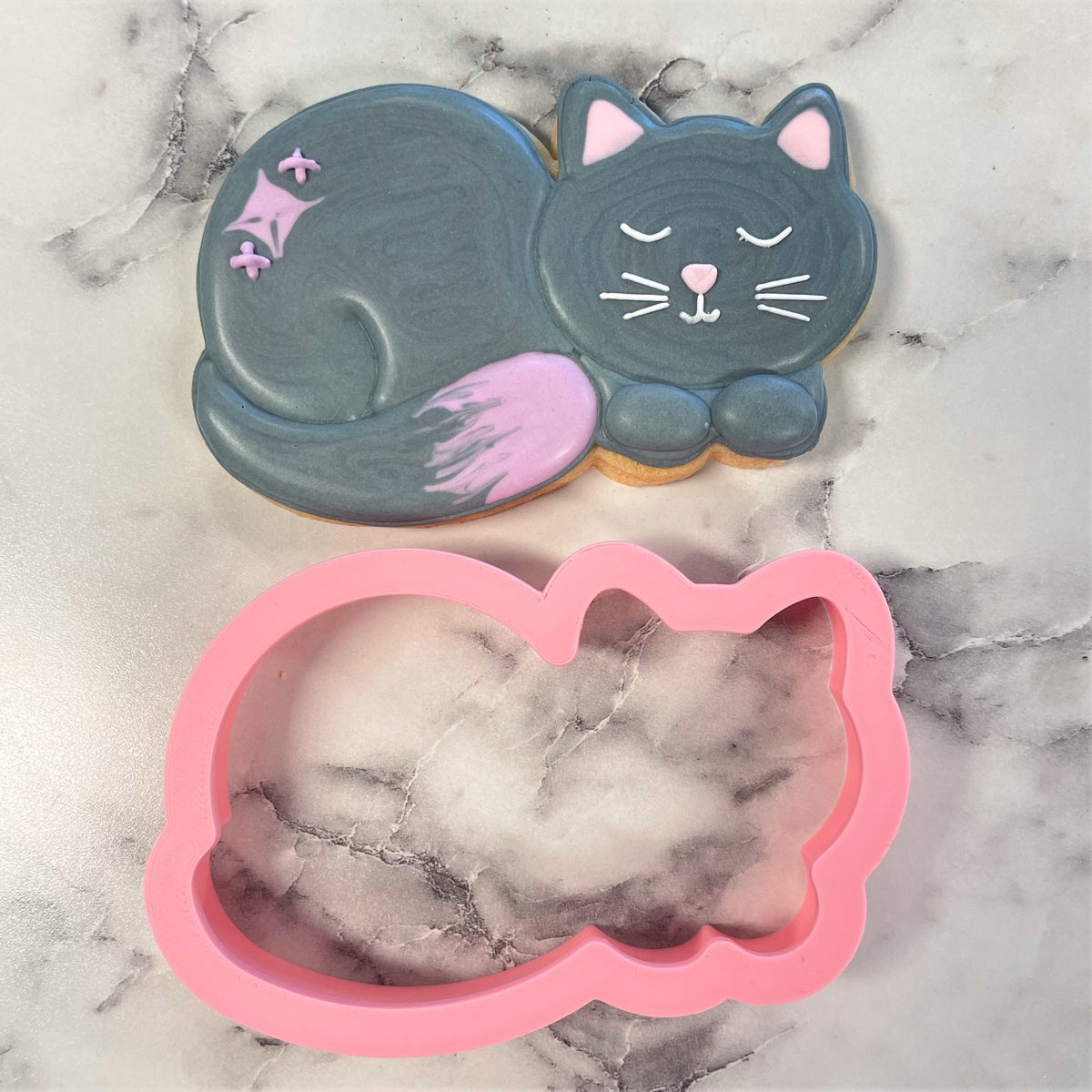 Pink silicone curled cat cookie cutter with a smooth flexible surface for baking and crafting purposes
