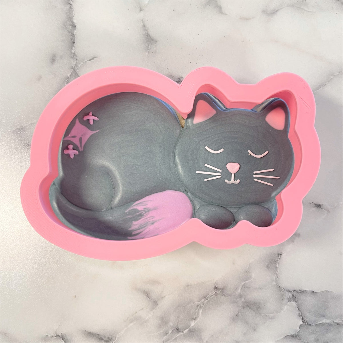 Curled cat cookie cutter pink silicone mold with gray interior featuring cat face with closed eyes and pink accents