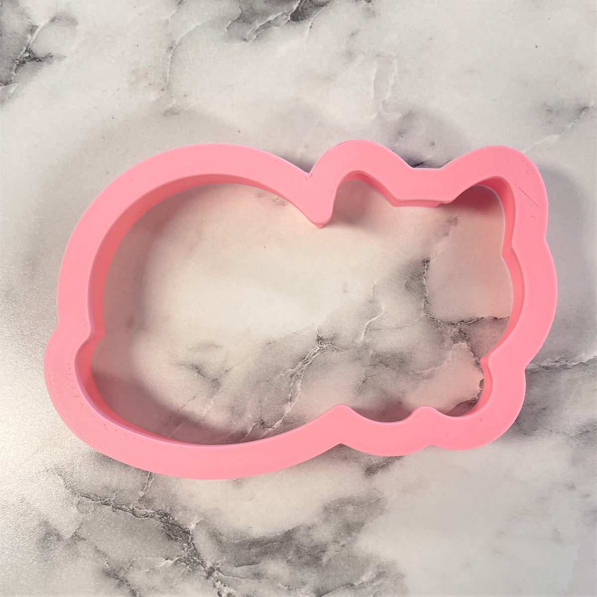 Pink silicone curled cat cookie cutter mold shaped like a sleeping cat for baking and crafting