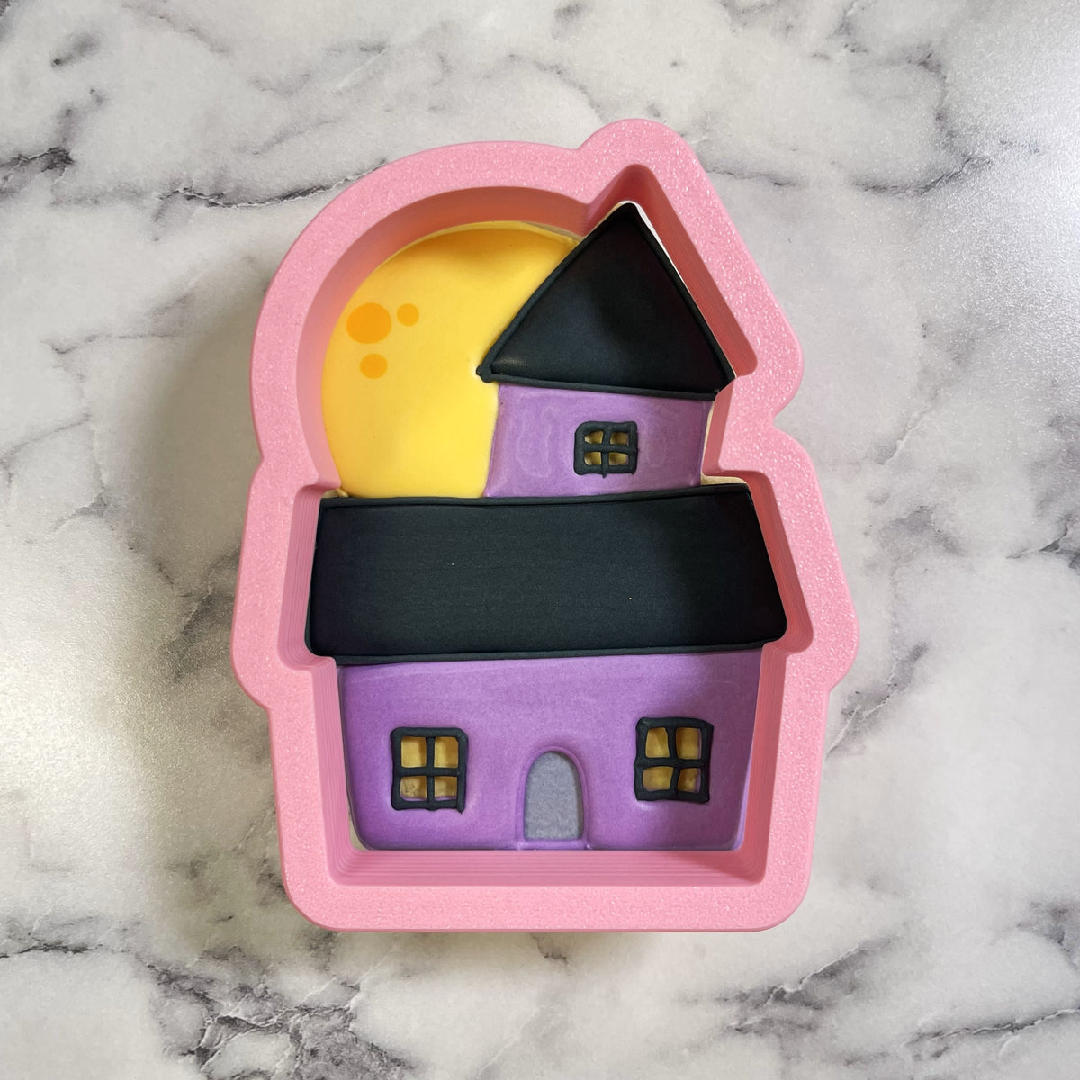 Cute chubby haunted house pink silicone baking mold with purple black details and yellow moon backdrop for halloween