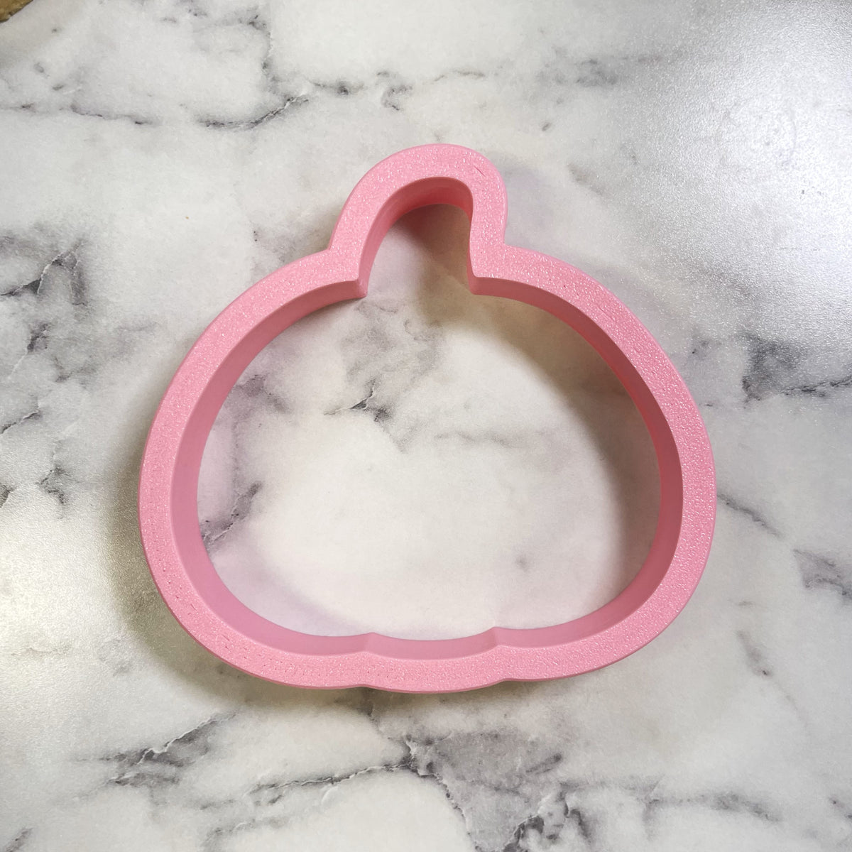 Pink silicone pumpkin-shaped cookie cutter with a cute chubby design for baking and crafting purposes