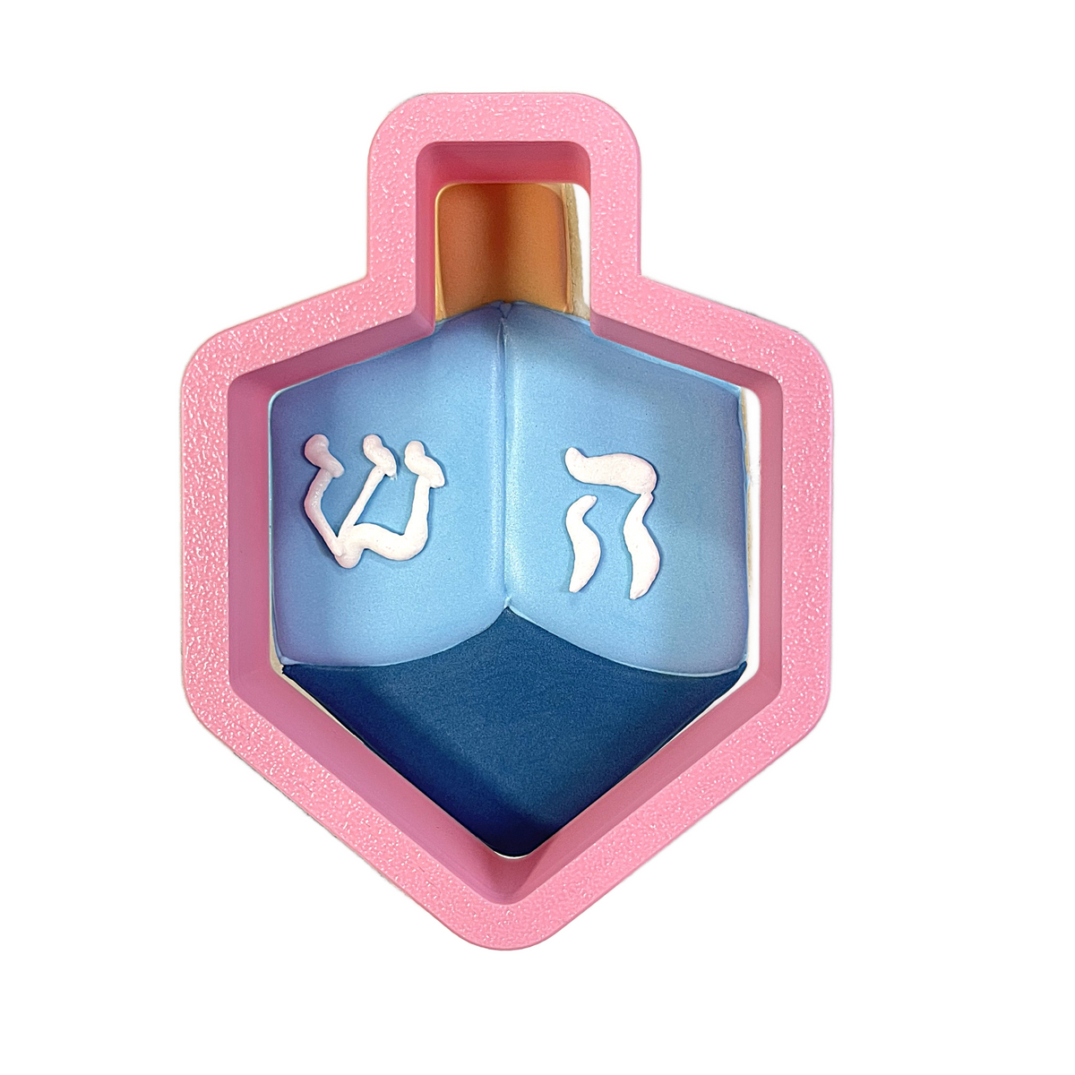 Pink hexagonal dreidel cookie cutter with blue and dark blue design featuring white hebrew letters