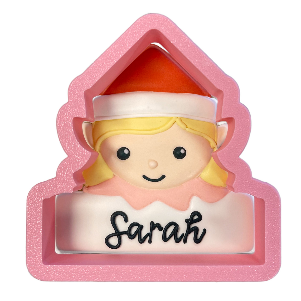 Pink house-shaped elf girl plaque cookie cutter featuring a smiling blonde elf with red and white hat personalized sarah