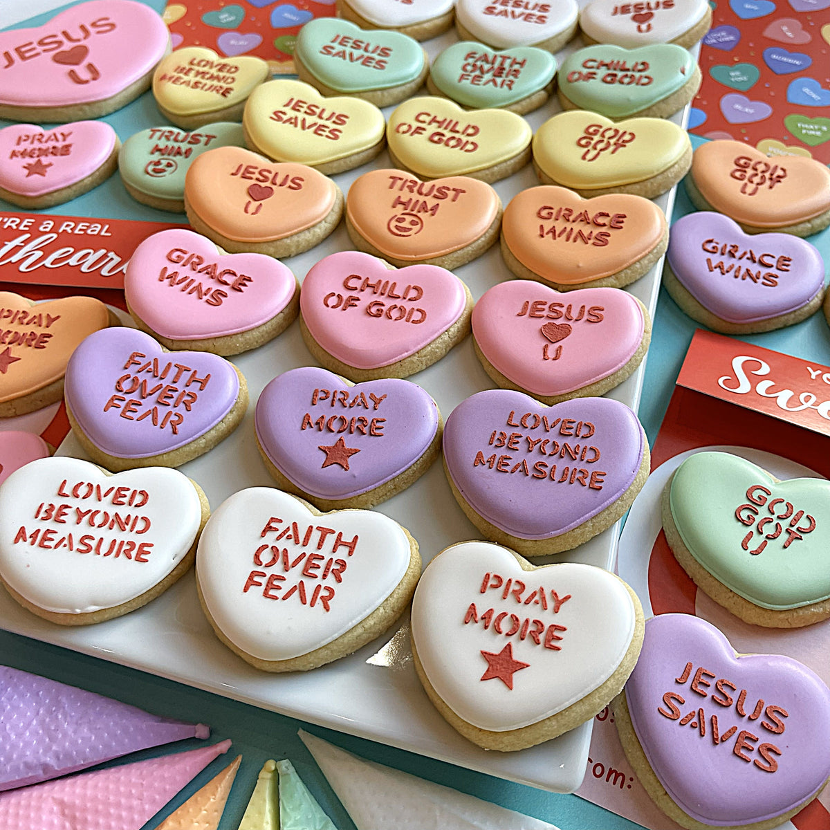 Pastel-colored heart-shaped sugar cookies with faith conversation heart small stencil messages jesus saves grace wins