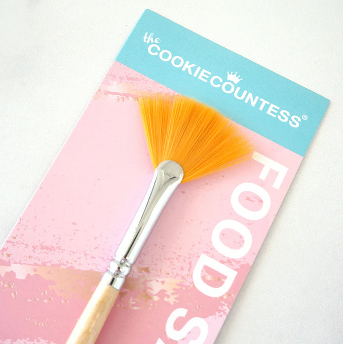 Orange fan brush with silver metal ferrule and wooden handle packaged in branded the cookie countess cardstock