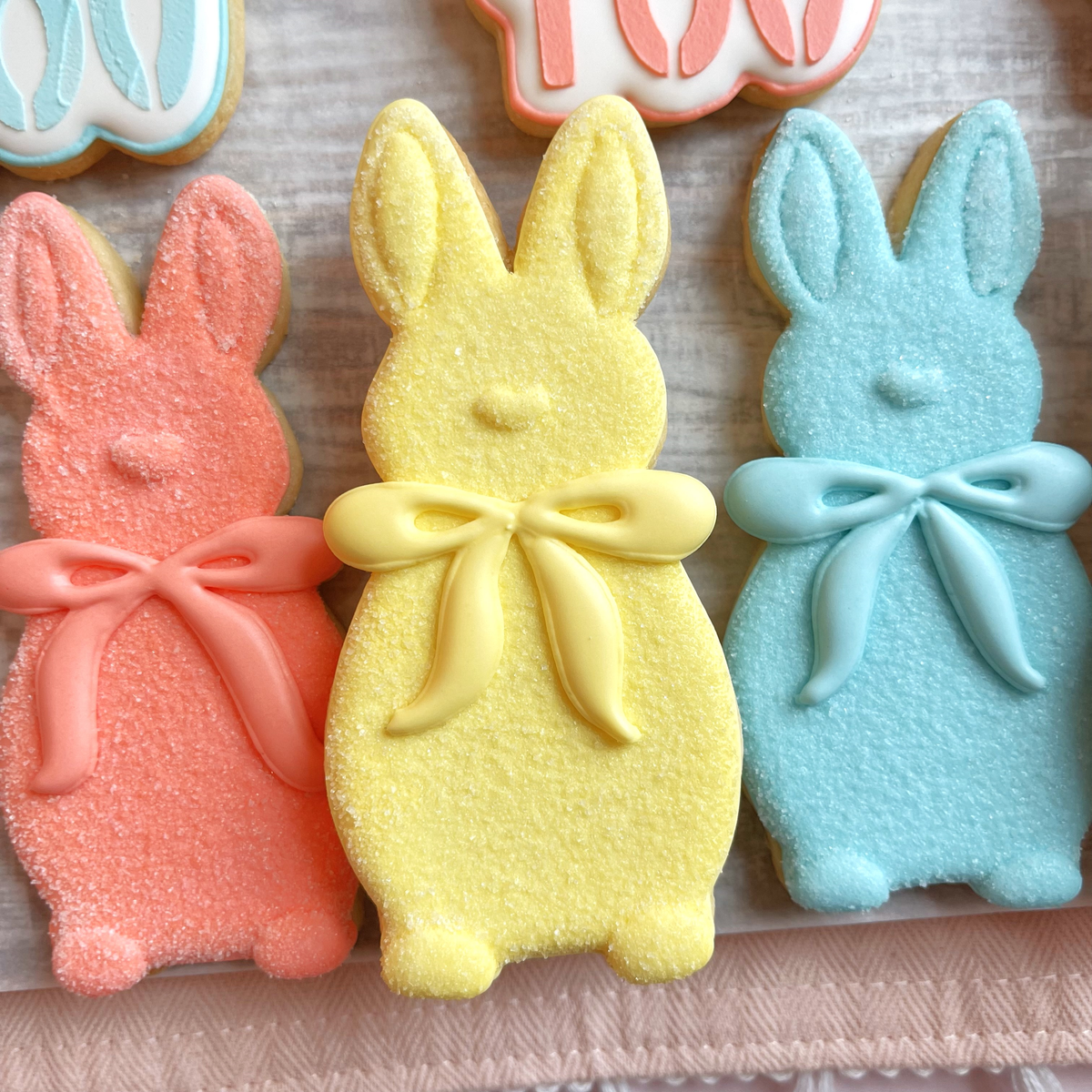 Pastel-colored sugar-coated easter bunny cookies with glossy icing bows made using a flocked bunny with bow cookie cutter