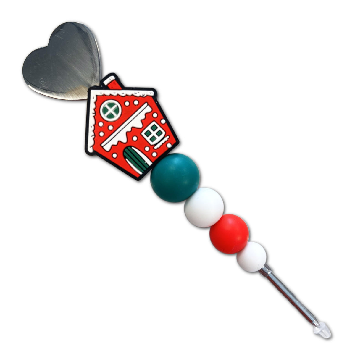 A festive red gingerbread house cookie scribe charm with white icing and green accents attached to a silver heart spoon handle