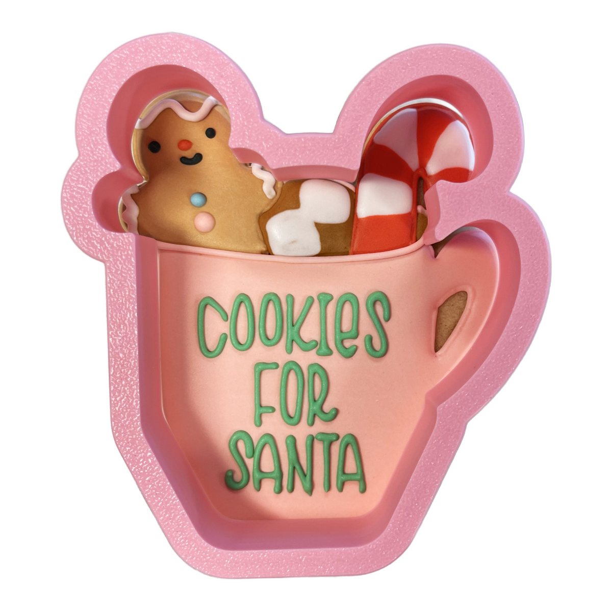 Pink glittery silicone hot cocoa with candy cane cookie cutter shaped like mug with green cookies for santa text holding gingerbread man and candy cane
