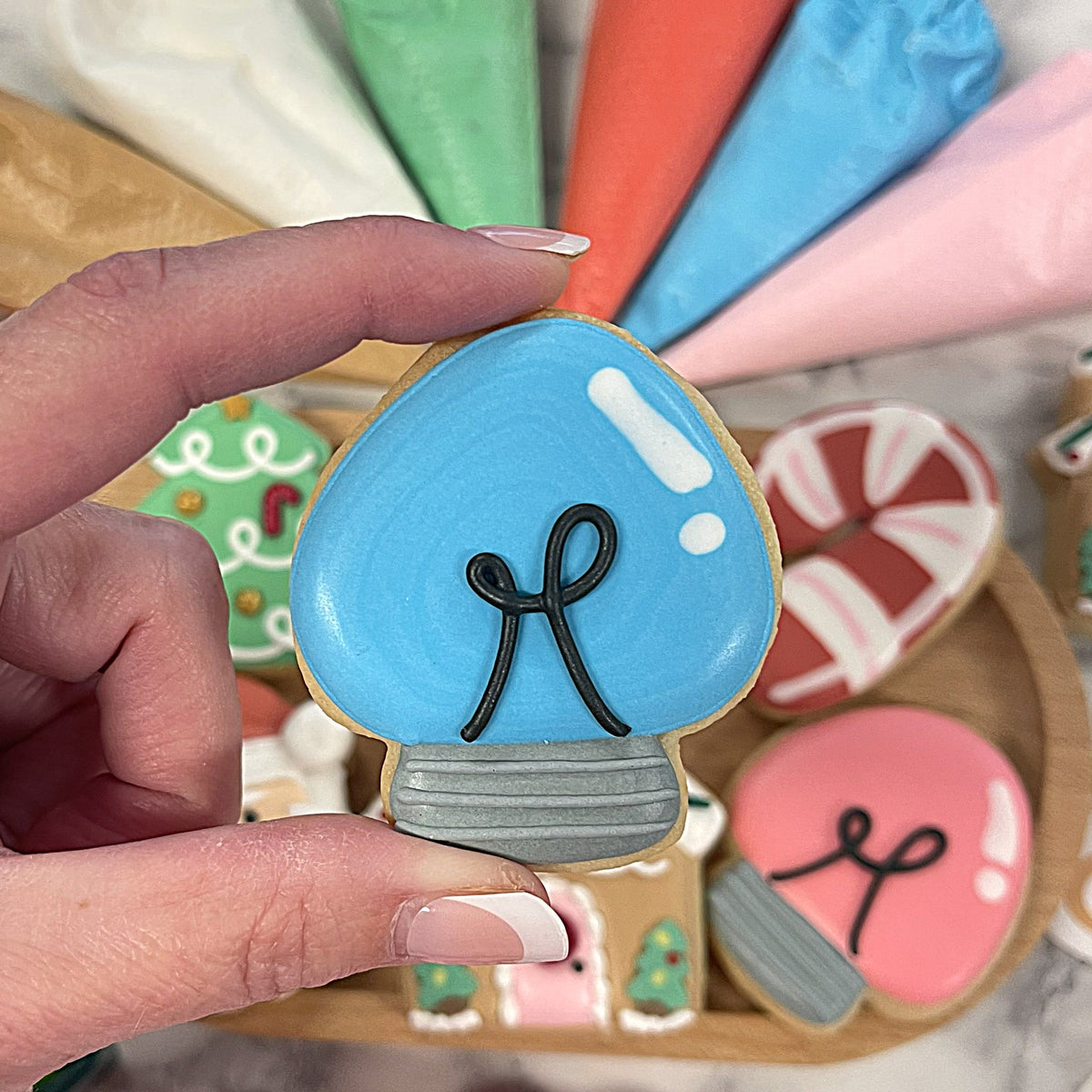 A blue frosted mushroom-shaped cookie with black icing letter h and gray striped base from mini cute christmas cookie decorating kit